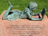Bronze statue of girl reading a book on a rock